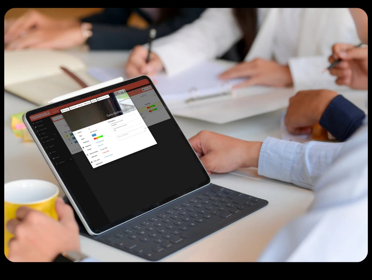 Réunion autour d’une tablette affichant la fiche détaillée d’une tâche dans Touch2build