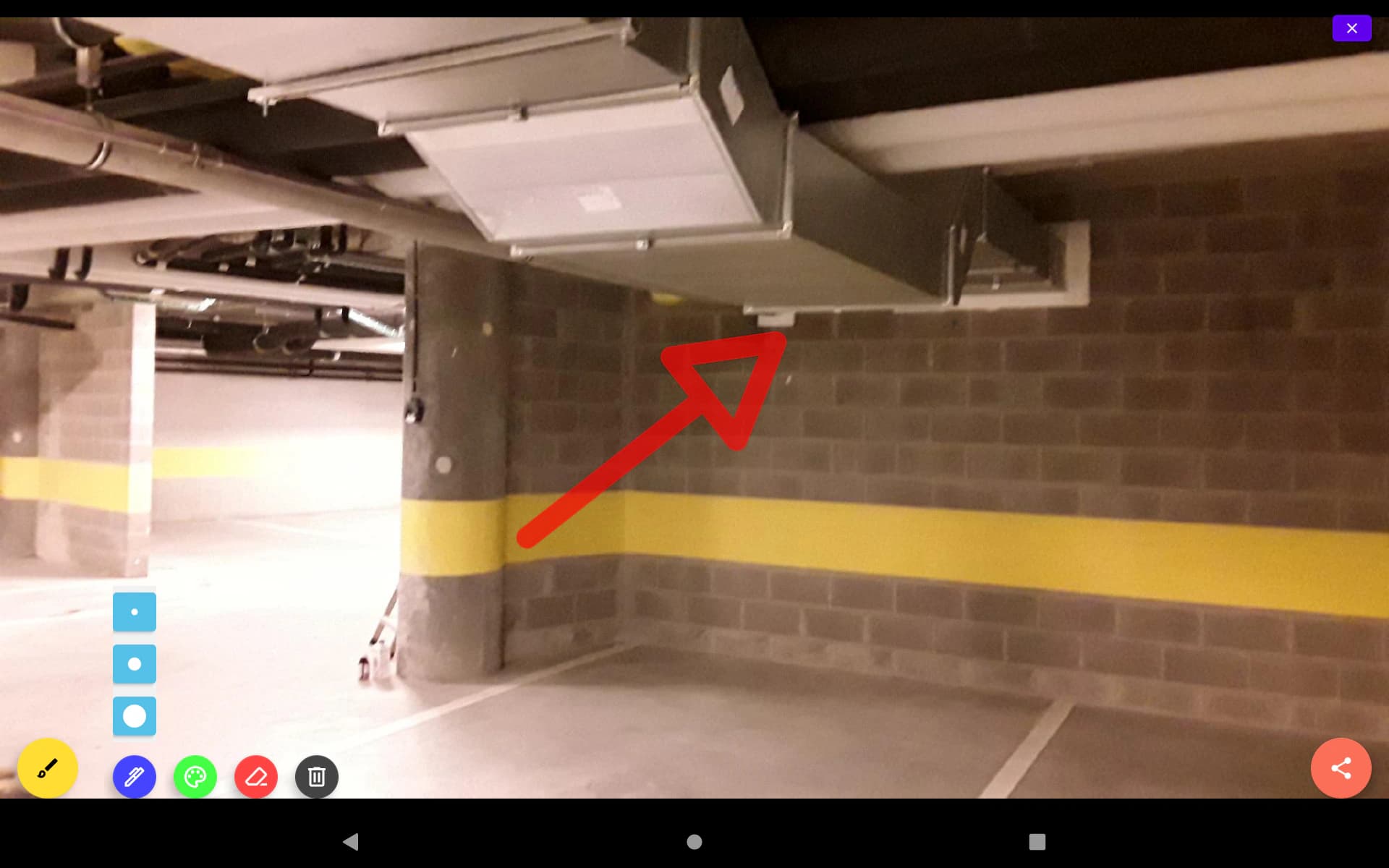 Photo d’un parking souterrain annotée d’une flèche rouge vers une gaine de ventilation